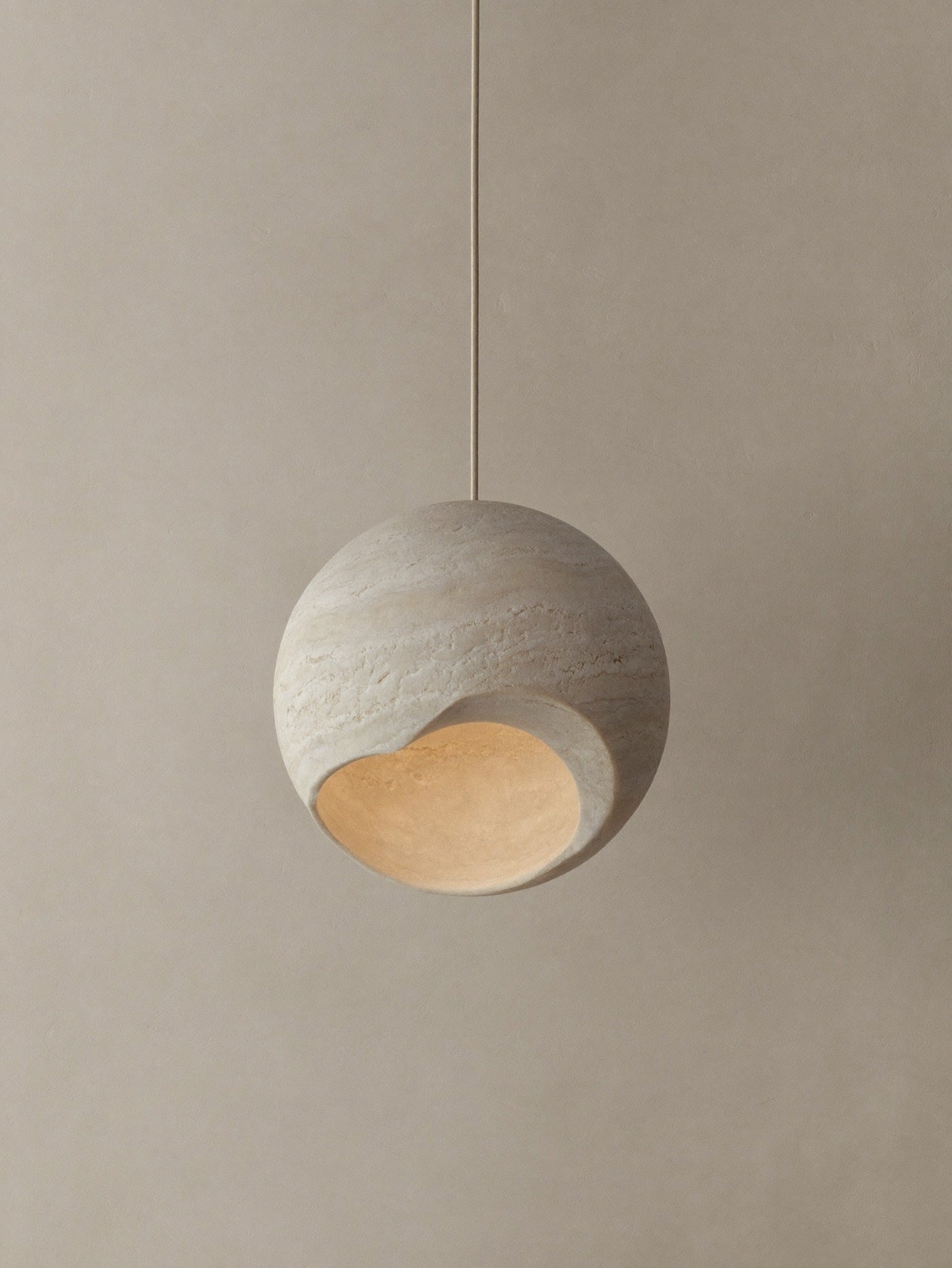 A carved travertine sphere pendant glowing softly