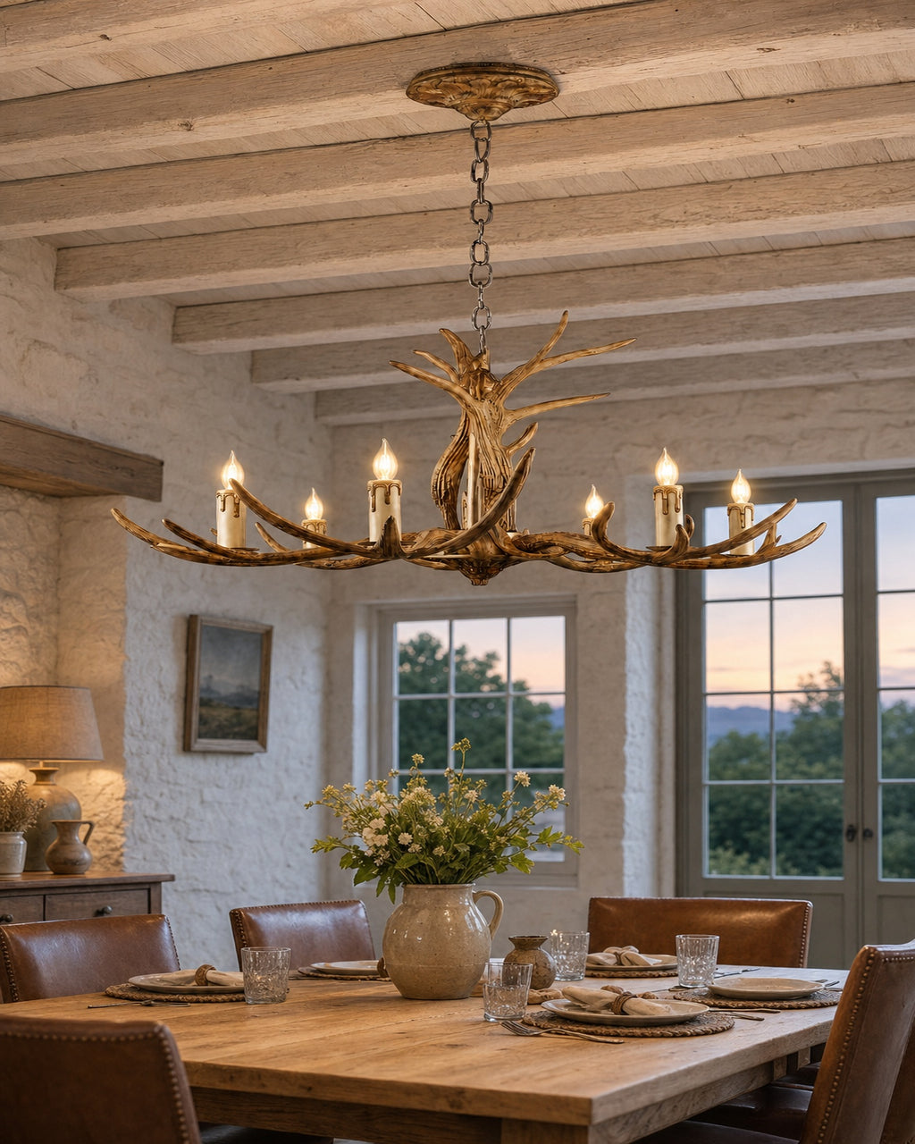 Rustic antler six-light chandelier lit warm over a dining table at dusk