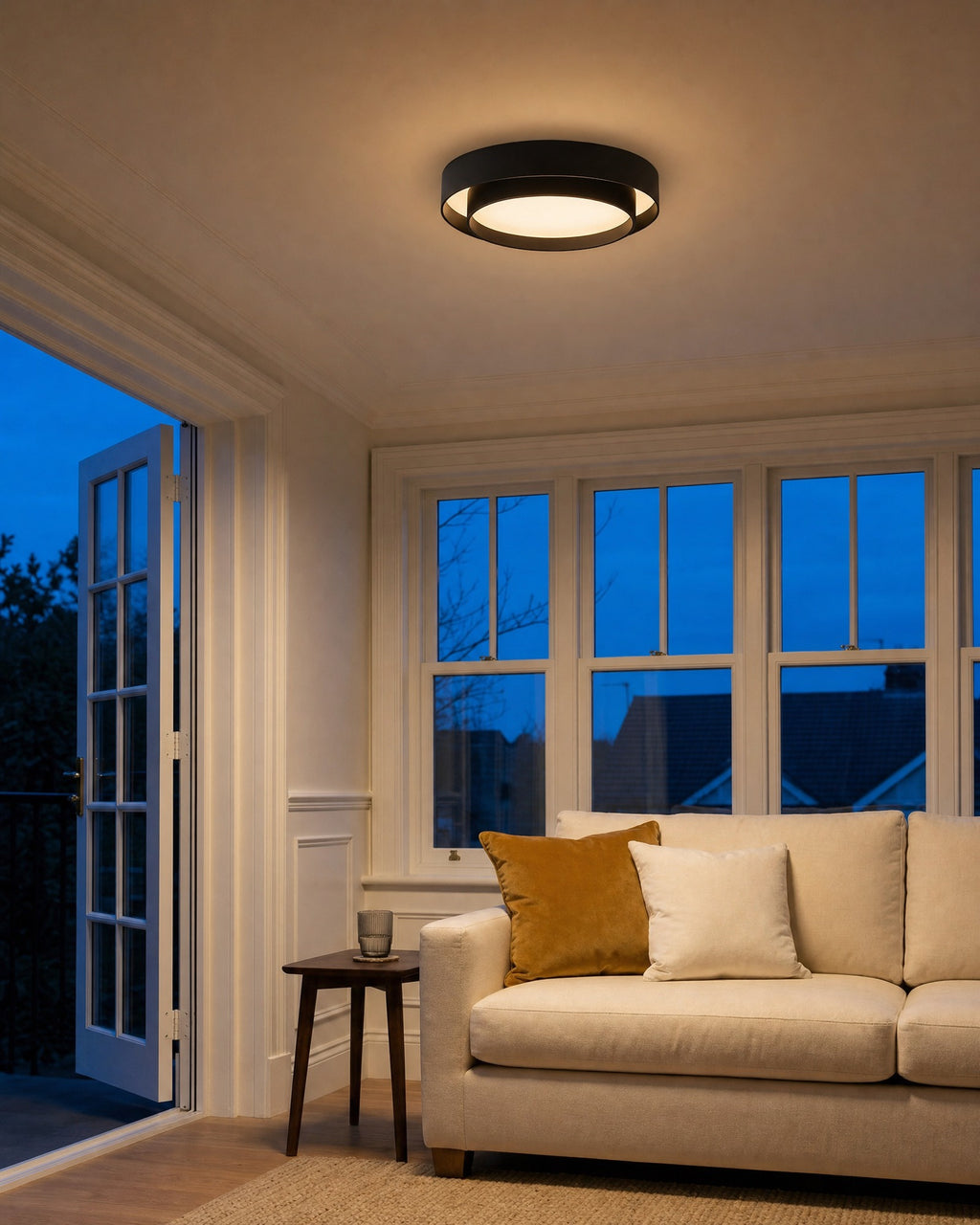 Black drum semi-flush ceiling light glowing in a living room at early evening