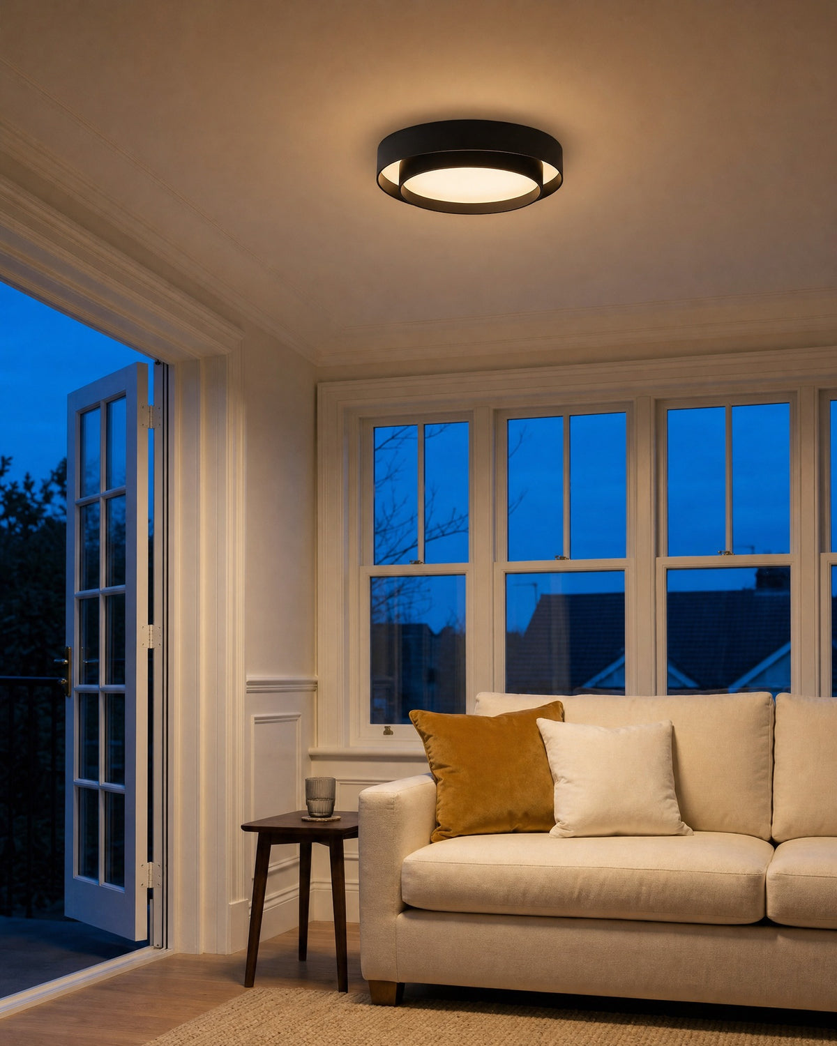 Black drum semi-flush ceiling light glowing in a living room at early evening