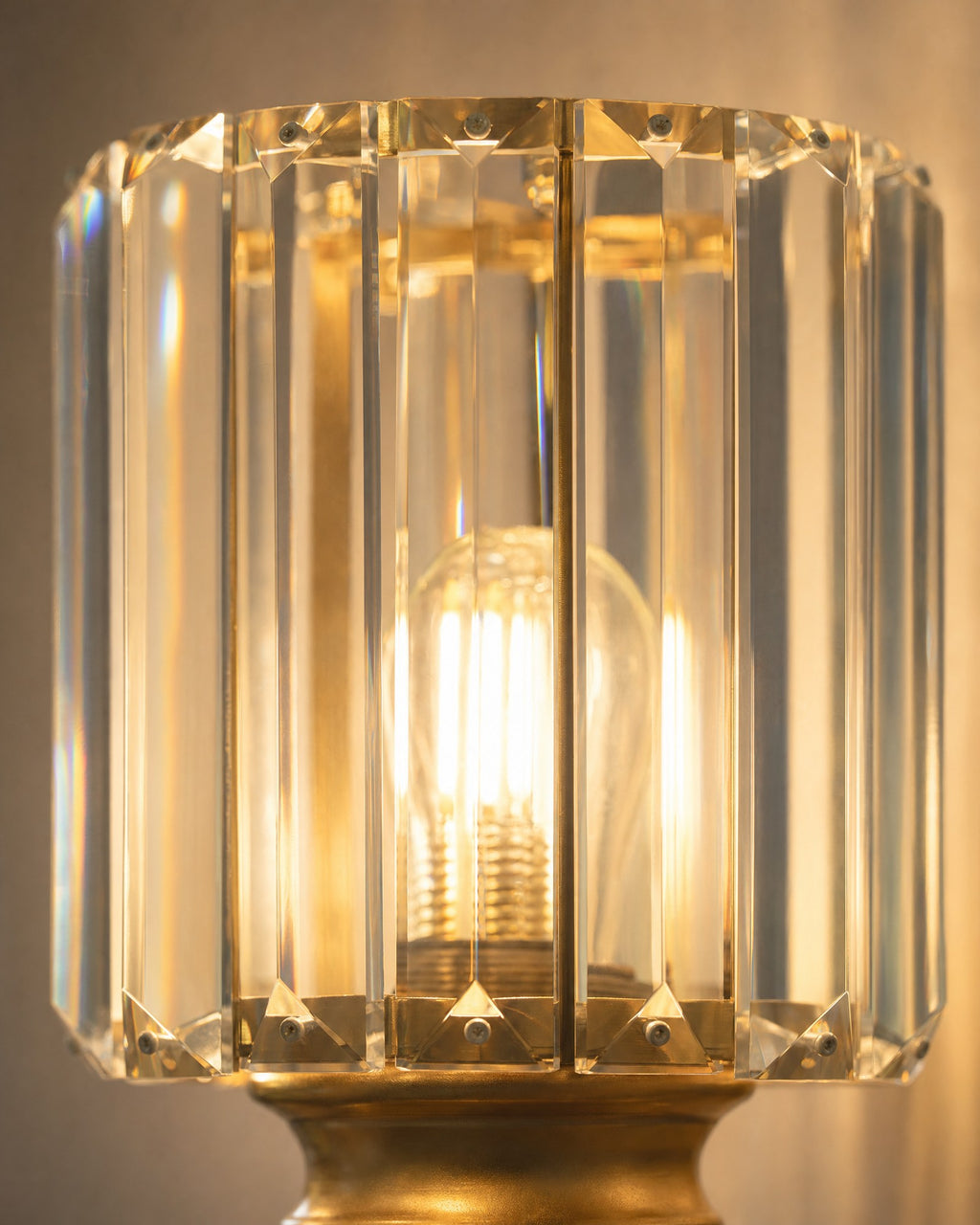 Macro close-up of the satin gold crystal cylinder Art Deco wall light shade, faceted crystal-effect prisms lit warm by an E27 filament bulb
