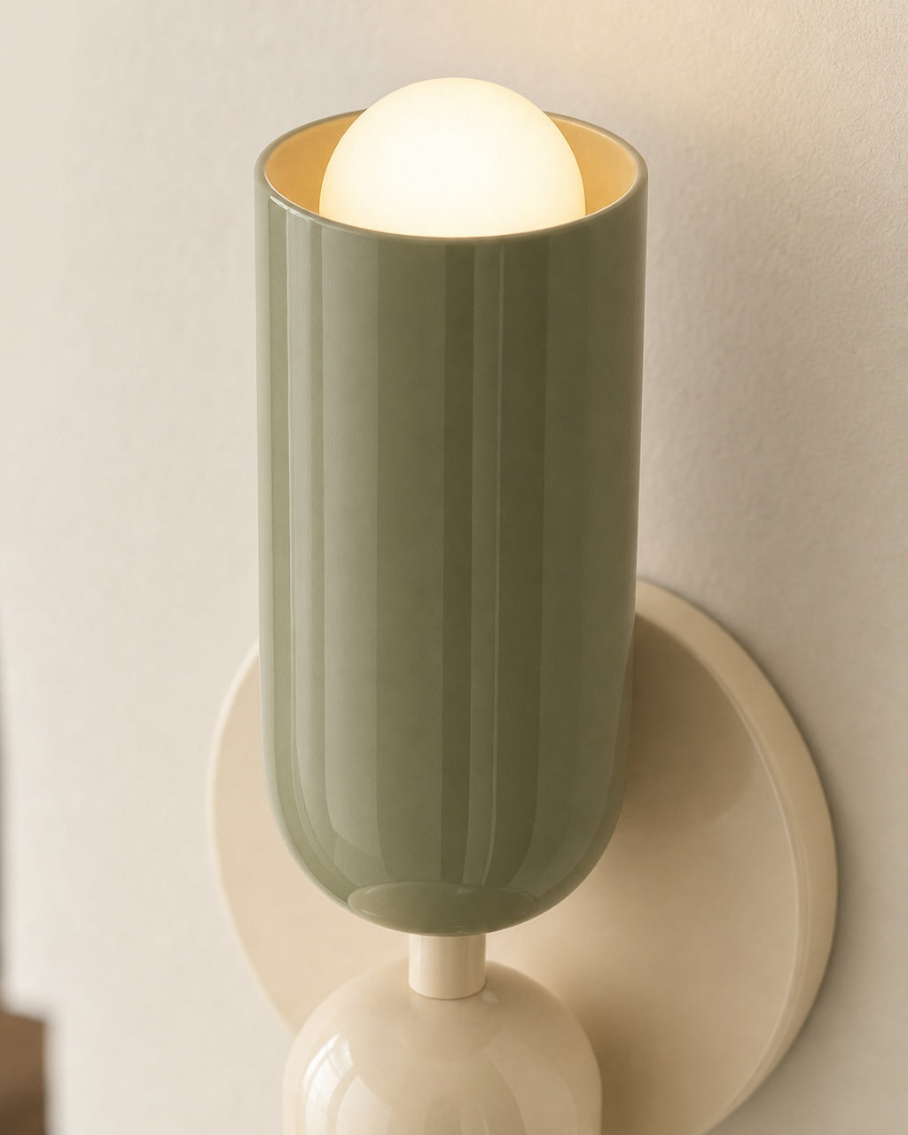 Close-up of the green painted upper shade with its opal globe, beige backplate and cream lower shade, lit