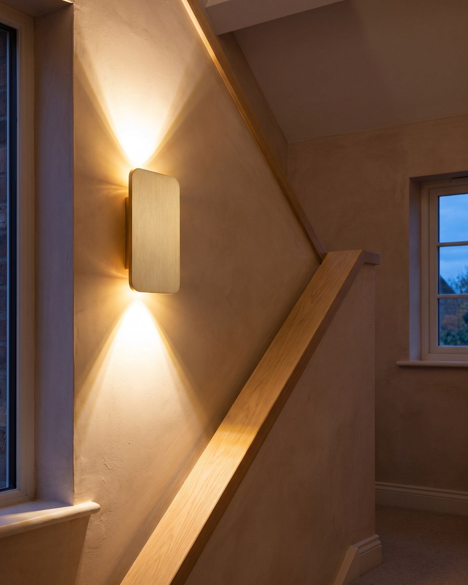 Brushed gold Nova wall light fanning warm light up and down a bright landing wall