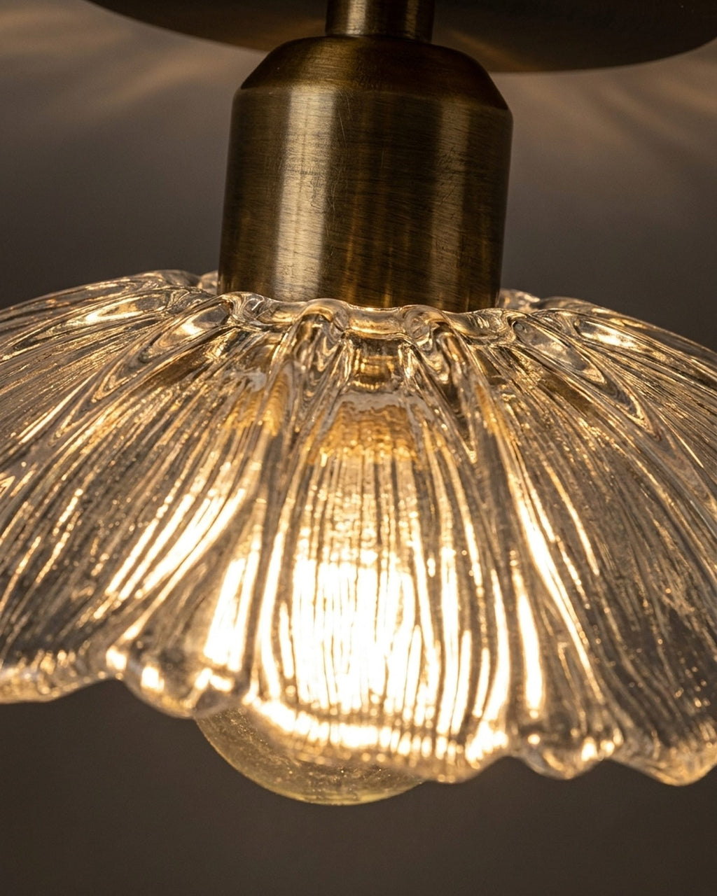 Macro of the fluted pressed glass and aged brass stem, lit warm