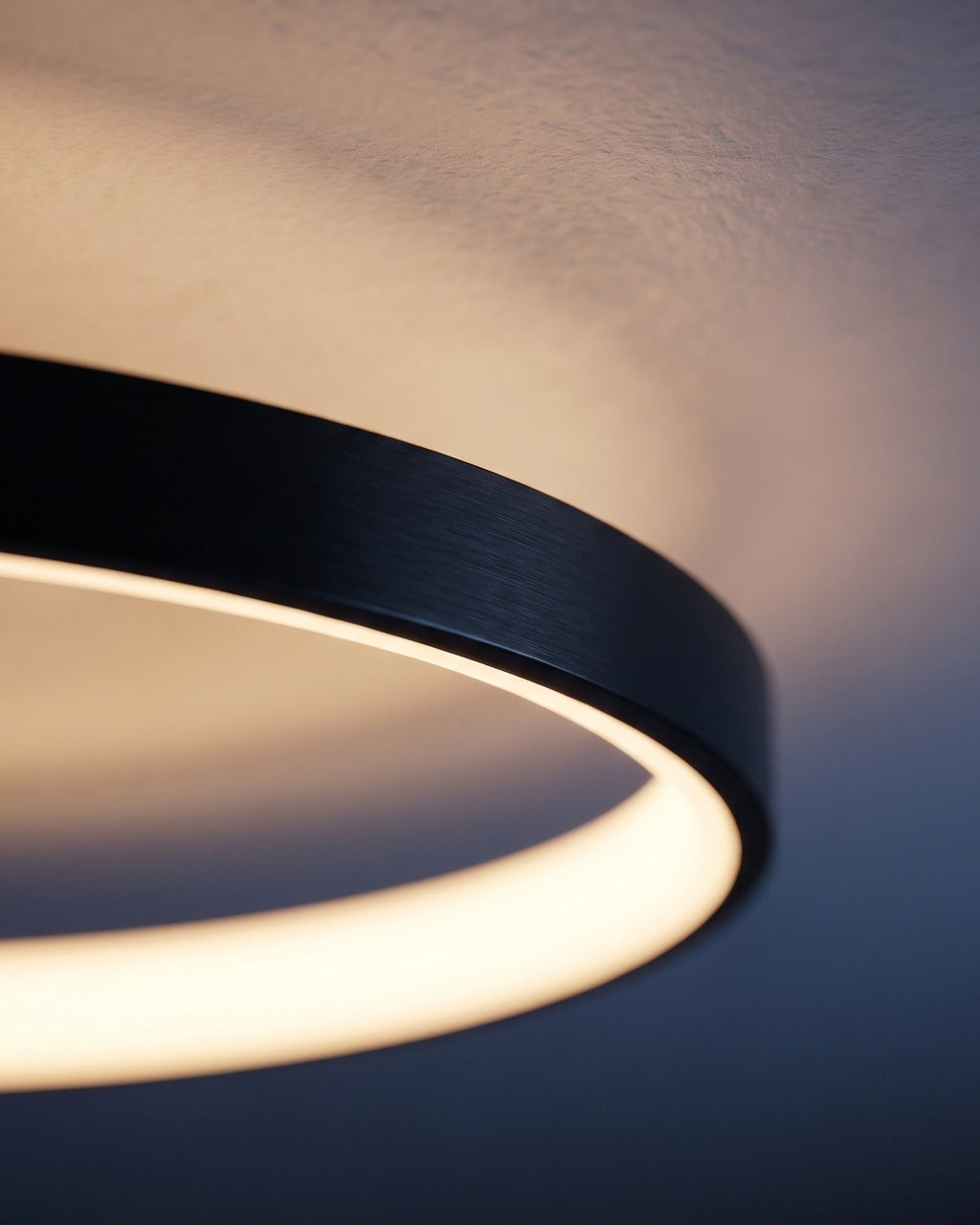Close detail of the Quasso ring — brushed matte black aluminium with a warm LED glow