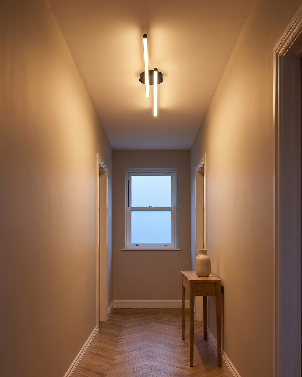 Twin-bar black LED flush ceiling light glowing warm in a hallway at early evening