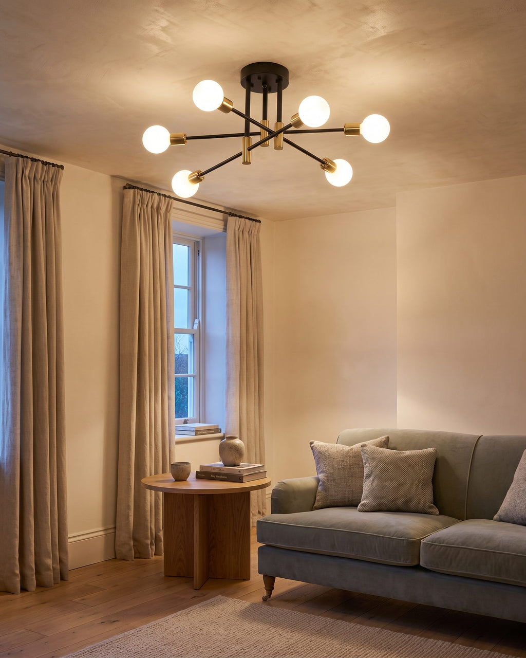 Black and gold sputnik ceiling light with six glowing globes in a living room at early evening
