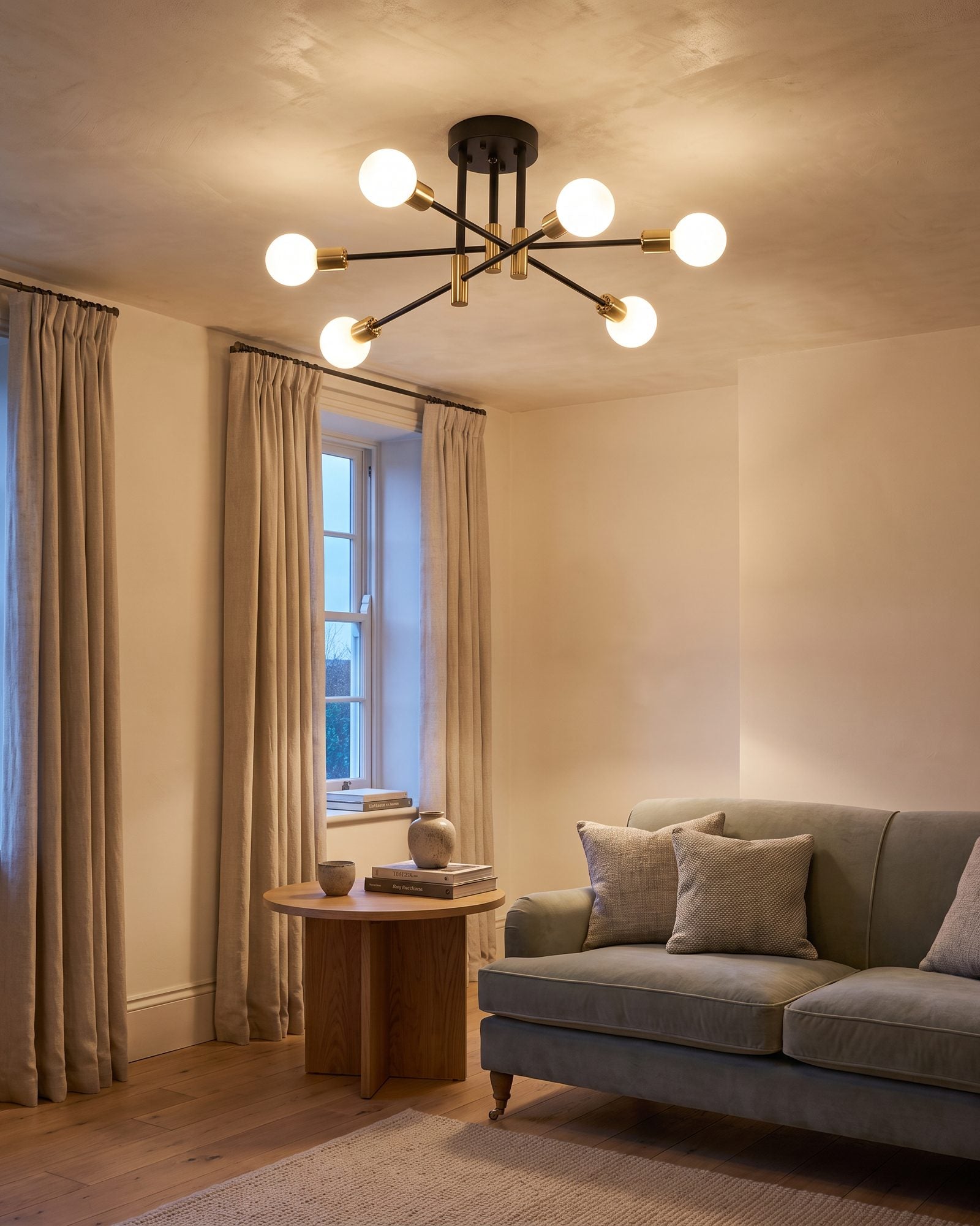 Black and gold sputnik ceiling light with six glowing globes in a living room at early evening