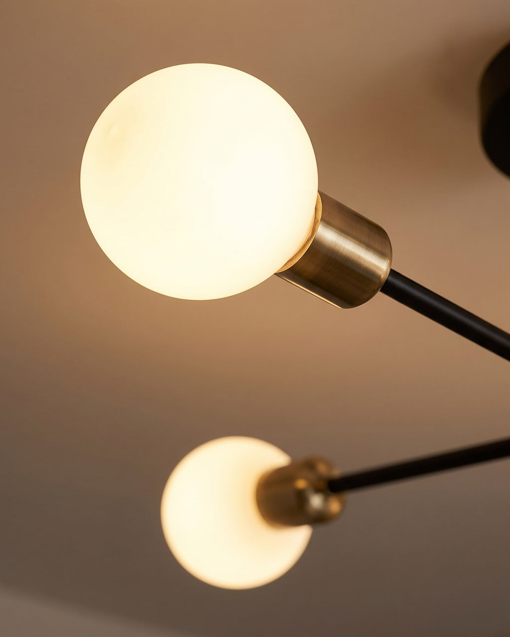 Macro of the brass socket, matte black arm and glowing opal globe