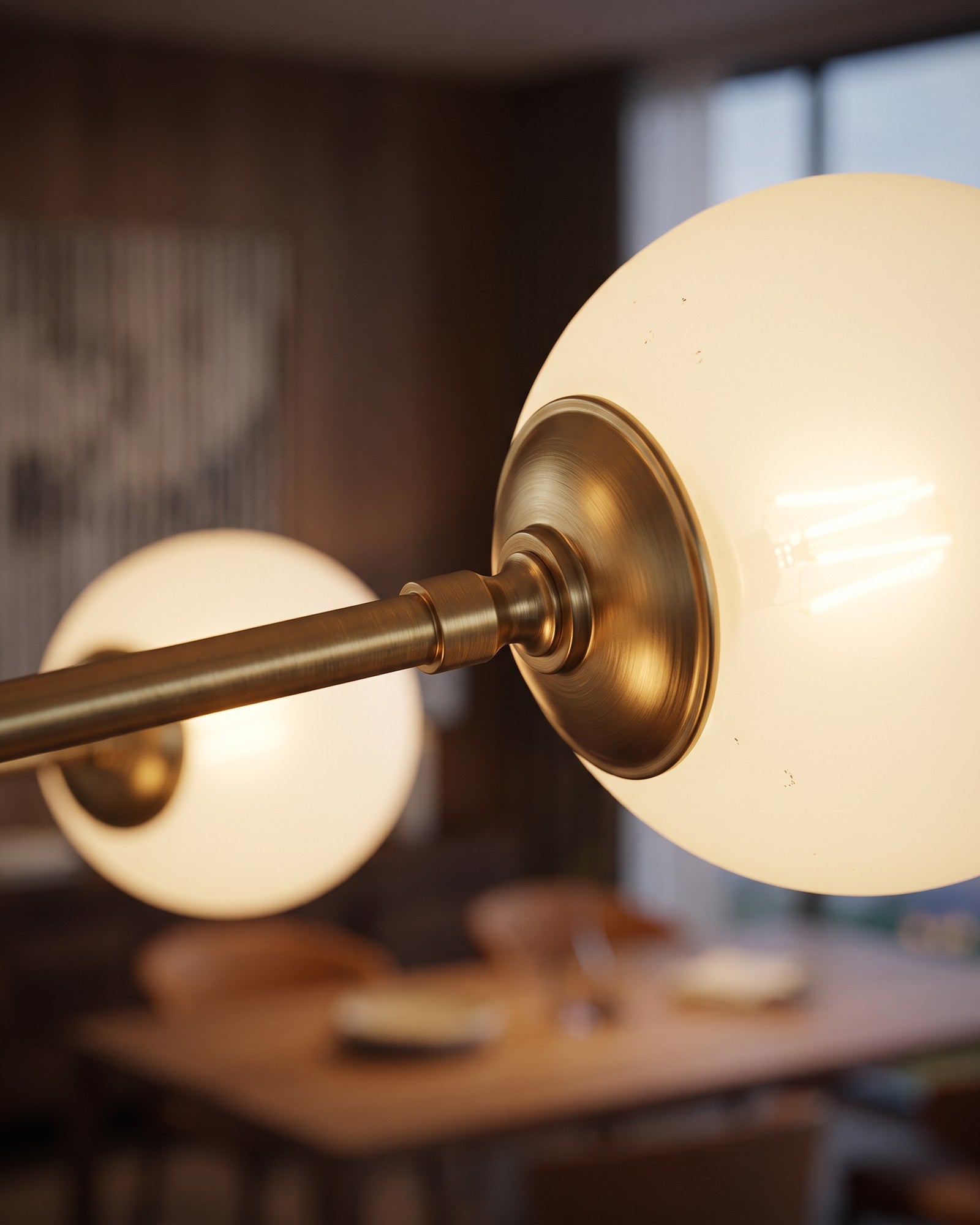 Macro of the brushed brass arm joint and glowing opal glass globe