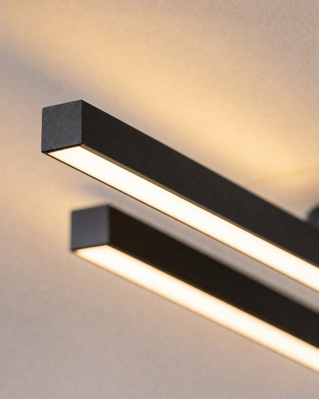 Macro of the twin bar LED flush ceiling light, two slim offset matte black aluminium bars with frosted LED diffusers glowing warm