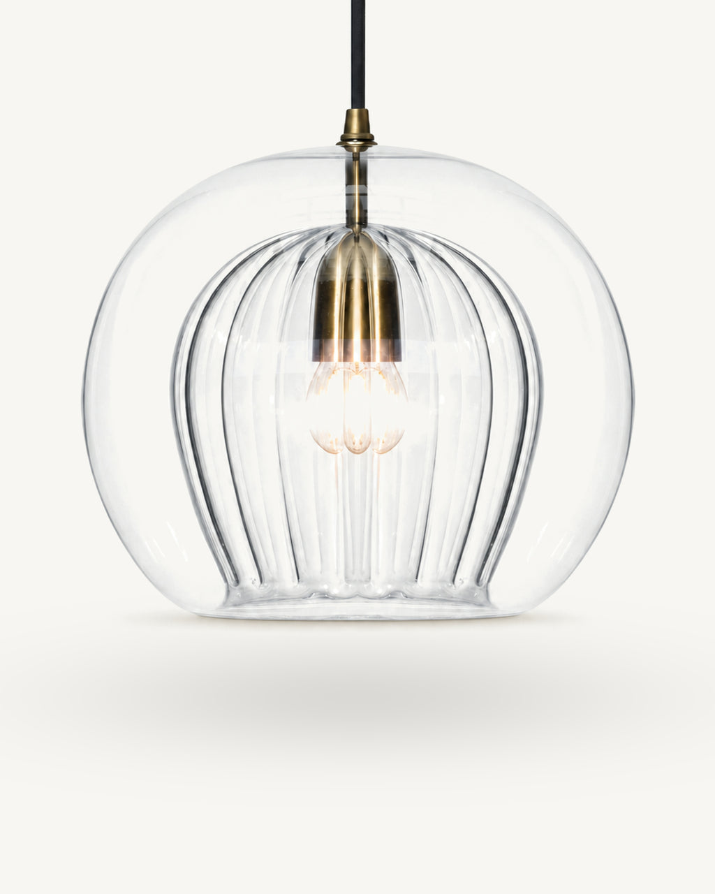 Zoey glass pendant light in Clear, a smooth outer glass globe over a ribbed inner shade, brass-finish lampholder on a black flex, shown against a plain light background.