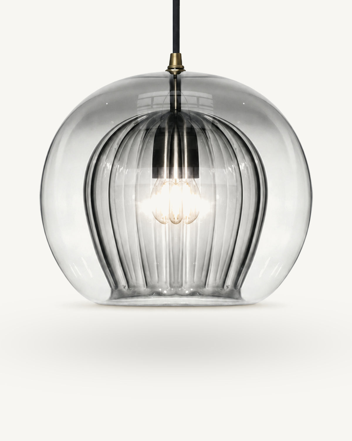 Zoey glass pendant light in Smoky grey, neutral grey smoked glass shading lighter towards the base, over a ribbed inner shade, brass-finish lampholder on a black flex.
