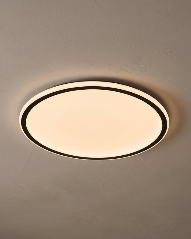 A slim black LED flush ceiling light glowing warmly