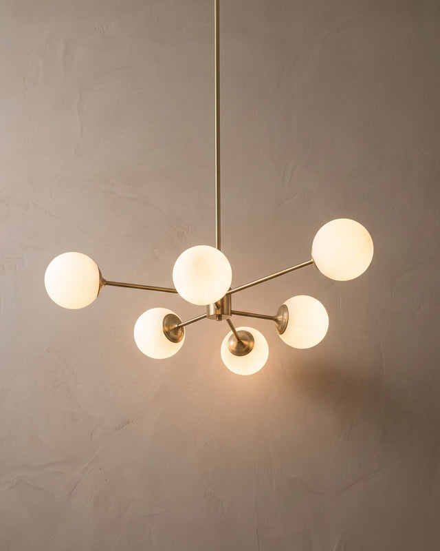 A brass six-arm chandelier with opal glass globes