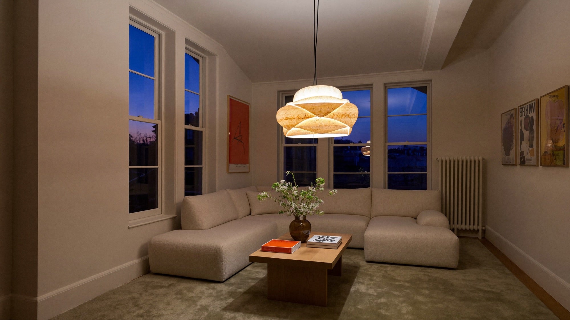 A sculptural pendant light glowing warmly in a calm London living room at dusk