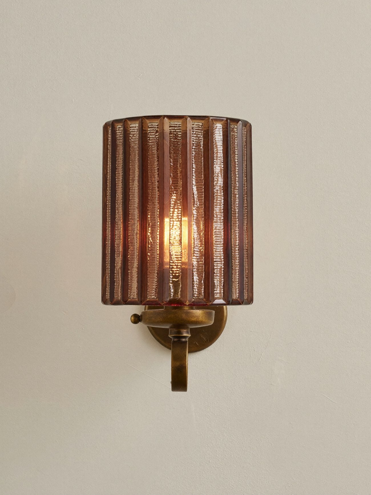A fluted amber glass wall light on aged brass